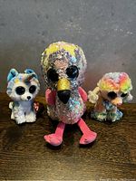 Photo of three TY brand plush toys: husky, flamingo, and poodle on a wooden surface.
