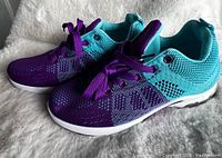 Pair of women's purple and turquoise running shoes taken from an angle showing side and top, highlighting colors and sole.