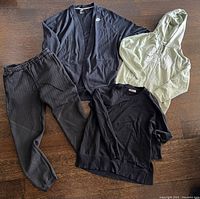 Four women's workout wear items laid out on wood floor: Nike jacket, GAP hoodie, Tuft sweatshirt, black pants.