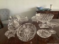 Photo showing all crystal items arranged on a table including compotes, pitcher, bowl, covered candy dish, basket, and serving dishes.