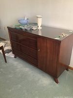 Front-right angle showing three drawers, cabinet door and glass top