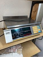 Photo showing the full front and top view of the Kubota LA-230 digital weighing scale placed on a shelf, includes the stainless steel weighing platform and power cord.