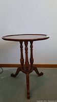 Side view of wooden clover leaf pedestal table showing turned legs and carved feet.