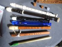 Seven woodwind instruments laid out showing materials and hole patterns