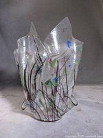 Front view of clear art glass vase with folded flame-like rim and multicolour abstract inclusions
