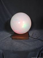Lamp lit showing multicolored glow from glass globe on wood base