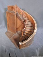 Overall angled view of miniature wooden spiral staircase showing curved wall and steps