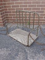 Front view of swing showing metal frame, wooden seat and chains