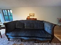Front view of antique blue velvet sofa showing the plush cushions, curved arms and the intricate carved wooden frame.