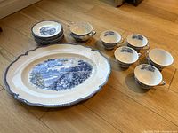 Photo showing a set of Johnson Bros dishes including small plates, teacups, saucers, a large oval serving platter, and a creamer. Blue and white English Gardens pattern visible on all pieces.