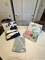 All four garments displayed together: blue pajama set, seafoam slip ensemble, pink bed jacket, grey robe