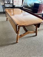 Coffee table with drop leaves in lowered position showing the polished solid wood surface and turned legs.