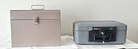 Side by side view of the Sentry Safe and metal document box closed on a white surface.