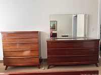 Dresser with mirror and 5-drawer highboy side by side against a wall, showing mahogany wood finish and drawer styles