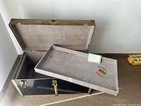 Open view of black steamer trunk showing patterned interior lining and removable shelf inside