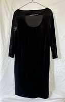 Black stretch velvet dress with peek-a-boo back detail, 3/4 sleeves, hanging on white background