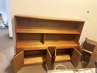 Pair of wooden bookcases showing upper shelves and lower cupboards with doors open