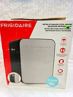 Box front showing Frigidaire branding and beverage refrigerator with stainless steel front panel and black sides.