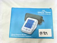 Photo of Easy@Home blood pressure monitor device in blue retail box with image of device on front.
