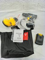 Photo showing cordless drill accessories including battery, charger, drill bits in yellow holder, user manual and carrying bag on white background