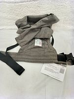 Gray Ergobaby baby carrier with attached tag indicating brand new condition.