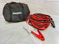 Energizer black carrying case with red trim and logo alongside coiled red and black jumper cables with vinyl-coated clamps and spring action handles.