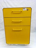 Front view image of yellow metal 3-drawer mobile pedestal file cabinet with handles and lock on top drawer.