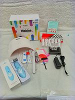 Overview of entire lot with LED nail lamp, multiple gel polishes, nail tools, power adapter, and electric nail clipper.