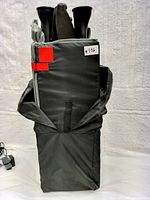 Folded and packed Harmony Play & Go Complete LT Playard featuring black fabric with red Velcro straps for compact portability.