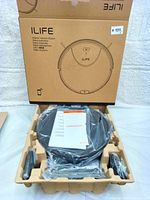 Robotic vacuum cleaner in open box with accessories and warranty papers inside molded fiber tray.