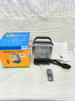 Photo of the search light with remote control, USB charging cable, instruction manual, and packaging box on a white surface.