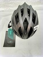 Top-down view showing gray textured helmet with ventilation slots and attached tag.