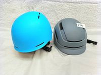 Two helmets pictured side by side: blue Outdoor Master on left and gray Ledivo on right, both medium size.