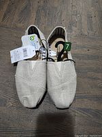 Front view of brand new beige women's size 7 shoes showing design, size tag, and price tag
