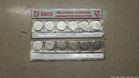 Two strips of six sealed Canadian quarters dated 2000 with commemorative designs for Millennium Quarters.