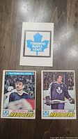 Front view of Toronto Maple Leafs logo card, Lanny McDonald and Darryl Sittler player cards showing player images and names