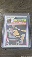 Front of the Mario Lemieux rookie scoring leaders card in protective sleeve showing player's image and card title.