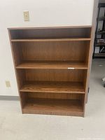 Front view of wooden bookcase showing four shelves and wood grain finish.
