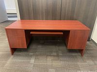 Front view of the wooden office desk showing two sets of drawers and a keyboard tray.