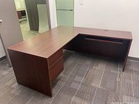 L-shaped desk showing top surface, drawers on left side, and keyboard tray on right side.