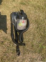 Photo of Bissell Aeroswift Compact vacuum cleaner with hose on grass.
