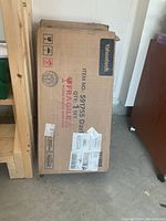 Photo of the Yaheetech cabinet in original cardboard box marked fragile with item number 591755 visible.