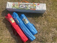 Photo showing the 6-person instant cabin tent bag and three camping chair bags (two blue, one red) on grass.