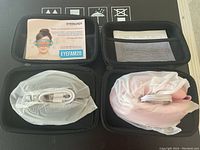 Top view of two Eyeology eye massagers wrapped in fabric covers with USB cables inside their cases, along with instruction card.