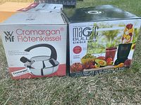 Photo showing boxed WMF Cromargan kettle and Magic Bullet Single Shot blender boxes side by side on grass.