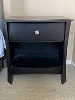 Front view of the bedside table showing the drawer with silver handle, open shelf, and curved legs.