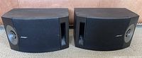 Pair of Bose 201 V speakers side by side facing forward showing front grills, bass port slots and midrange driver openings.