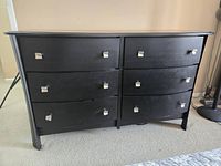 Front view of the 6 drawer black dresser showing drawer arrangement and silver knobs.