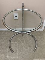 Front angle of the round glass and metal end table showing the circular base and metal frame