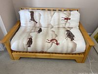 Futon with light wooden frame and mattress with animal figure print design, showing full width from front.